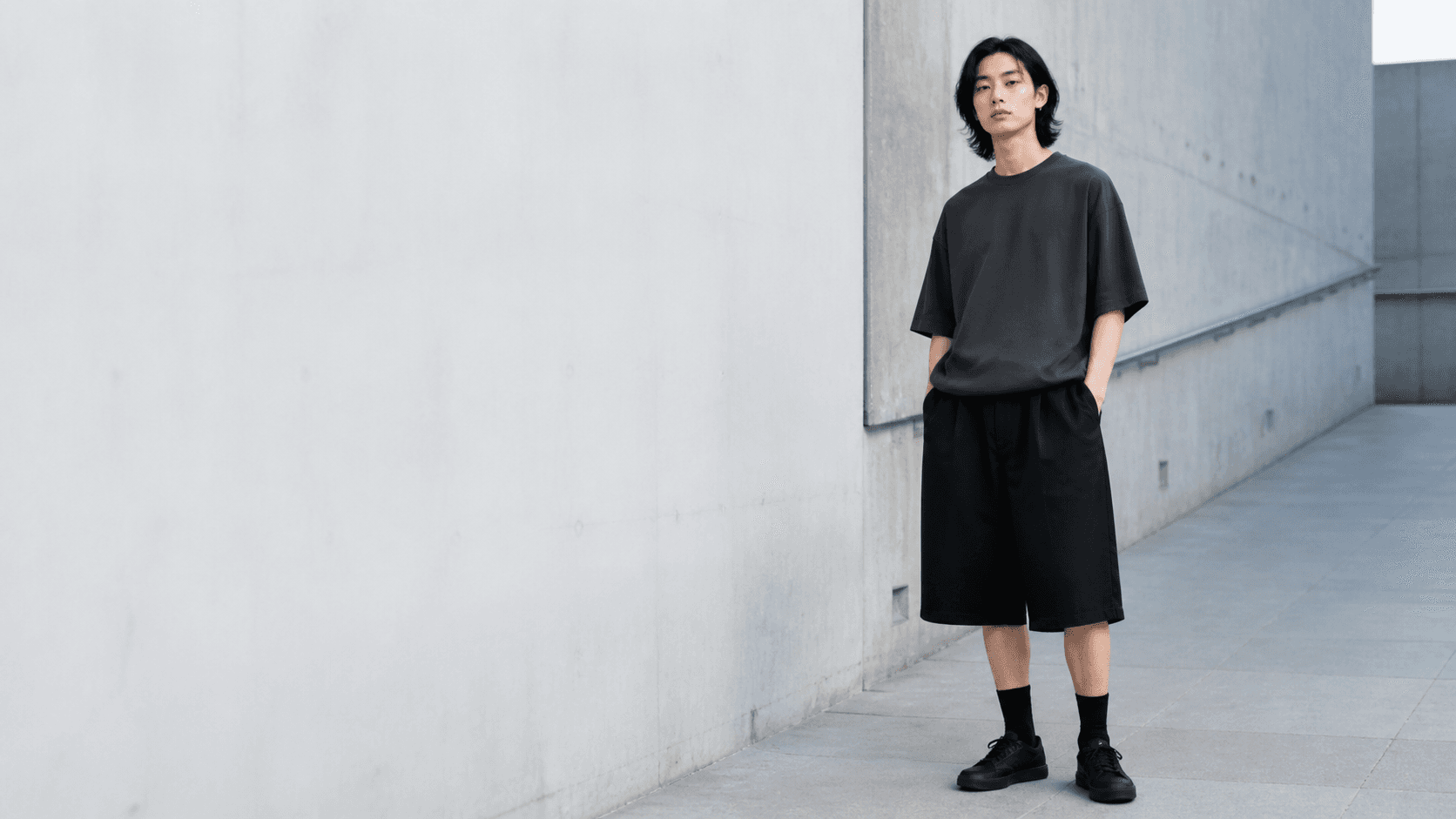 Model in a graphite oversized top and black Bermuda shorts